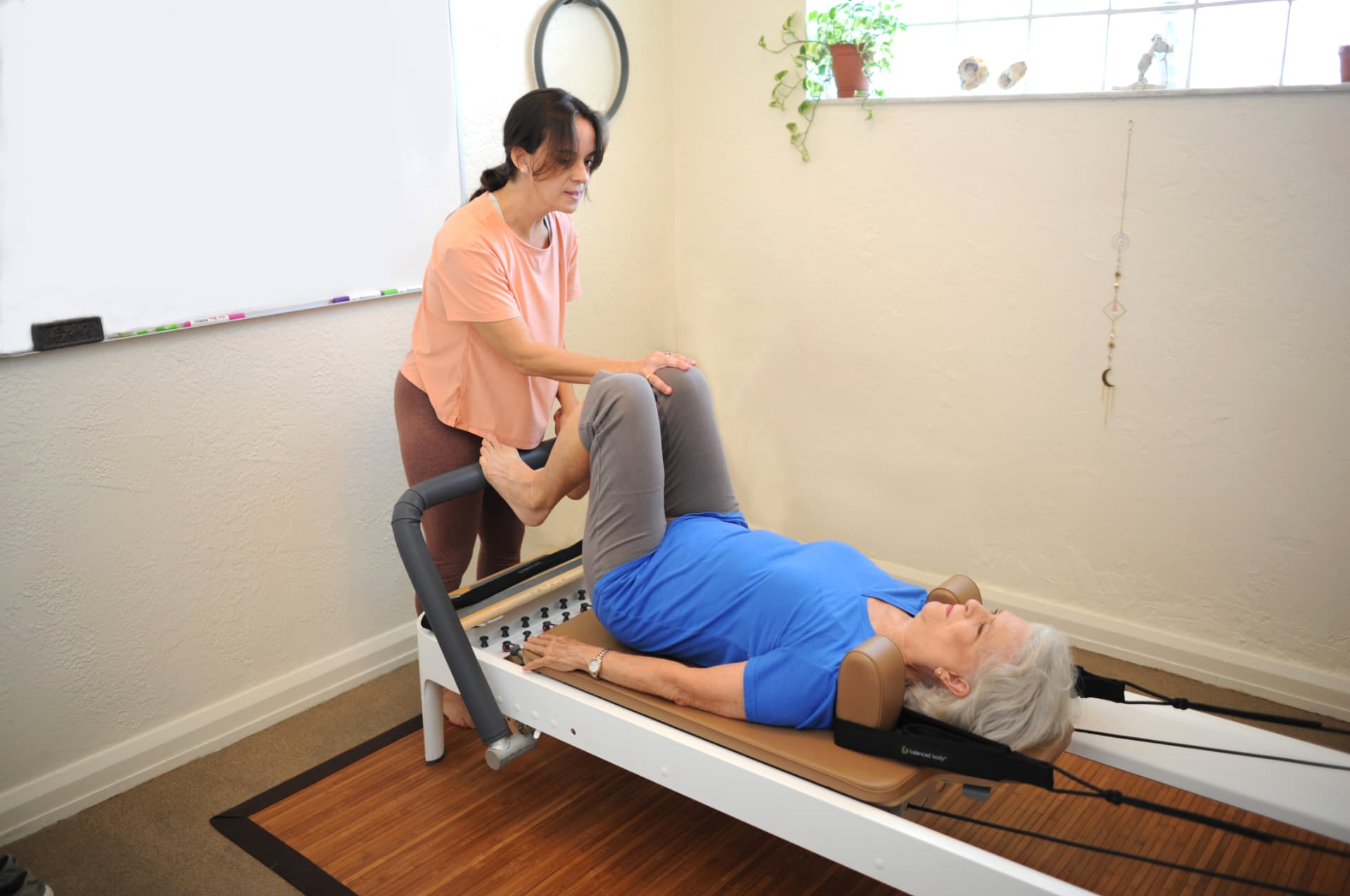 Client on the reformer receiving hands-on cueing from Ivonne